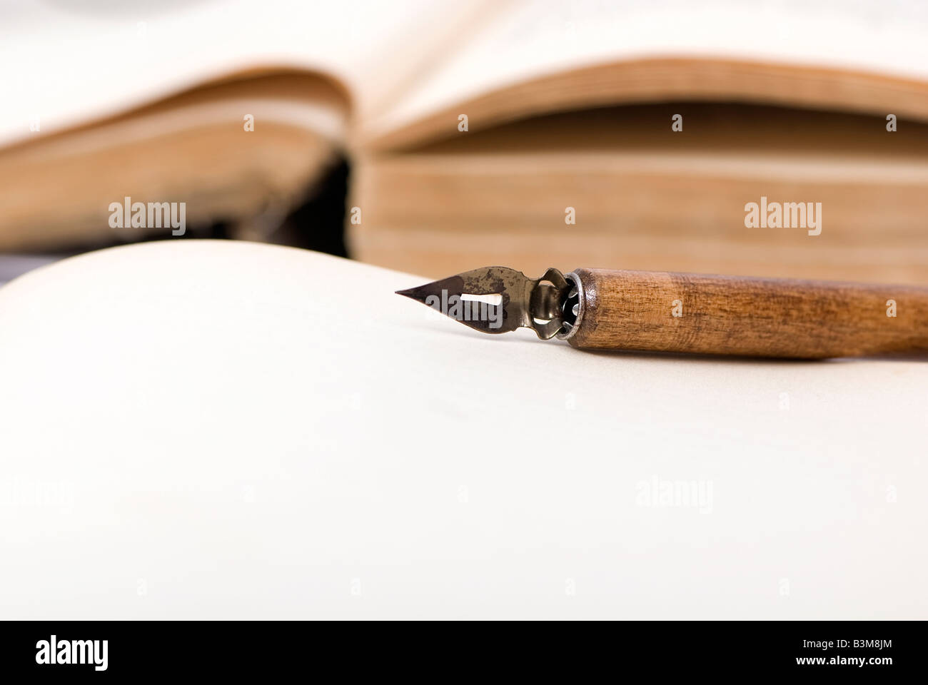 Ein altes Buch, das mit einer Kalligraphie-Feder an der Spitze geöffnet ist Stockfoto