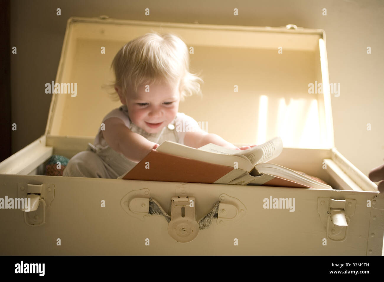 Ein Kleinkind, das ein Buch in einer Hoffnungsträger liest. Stockfoto