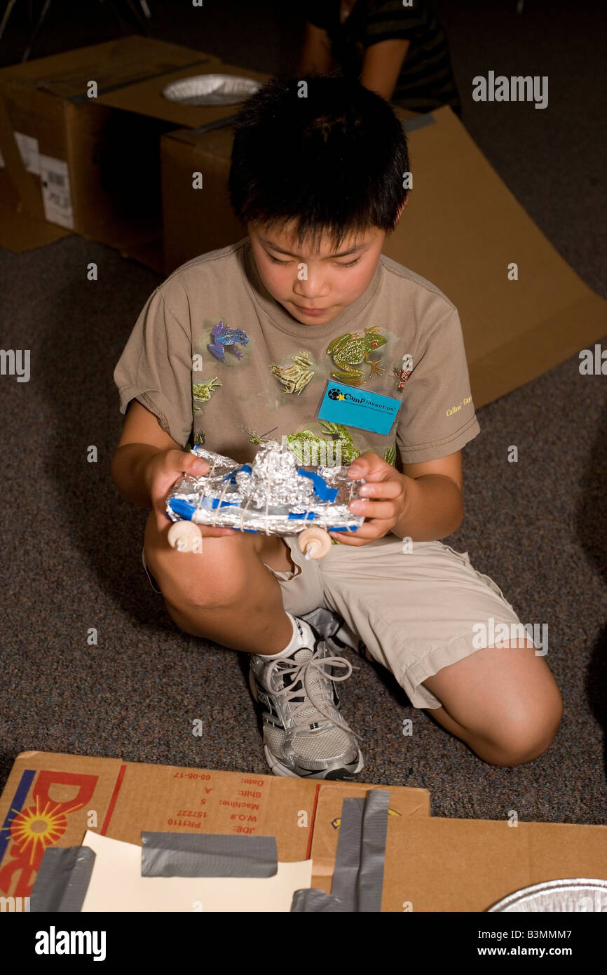 zehn Jahre alten Jungen auf Modellfahrzeug aus recycelten Materialien in der Schule arbeiten Stockfoto