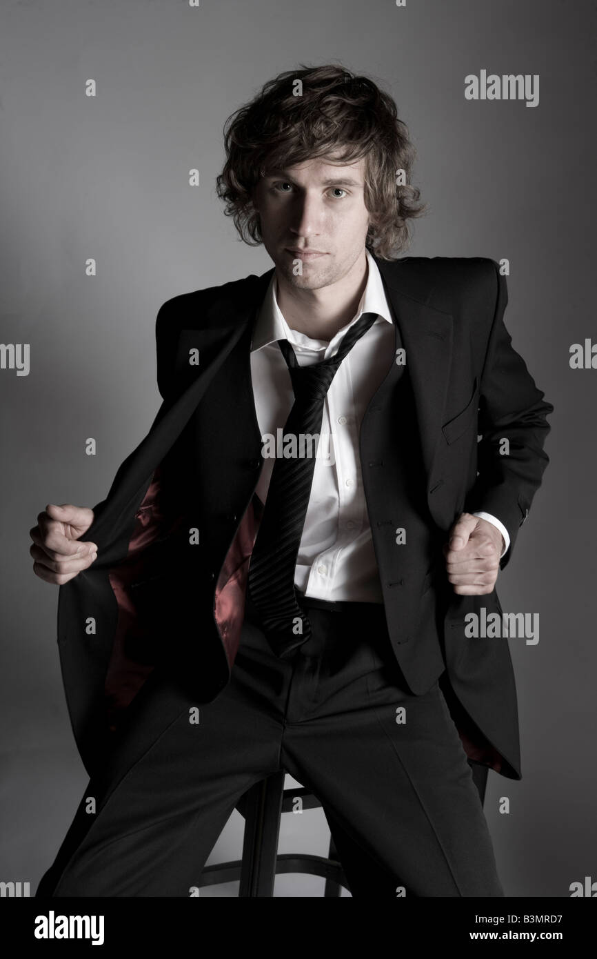 junger attraktiver Mann sitzt auf Stuhl eine dreiteilige Anzug Stockfoto