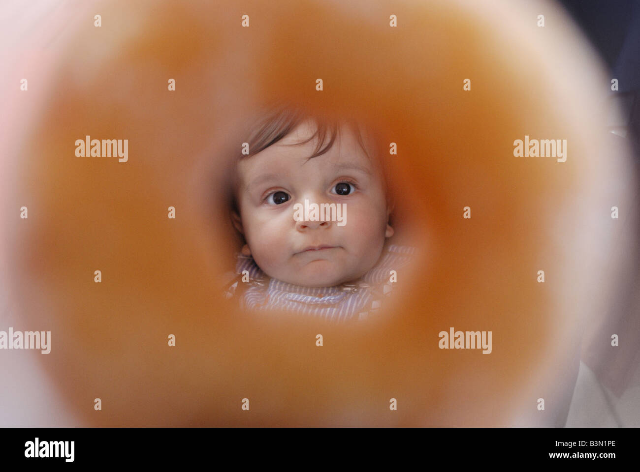 Baby schaut durch einen Donut Stockfoto