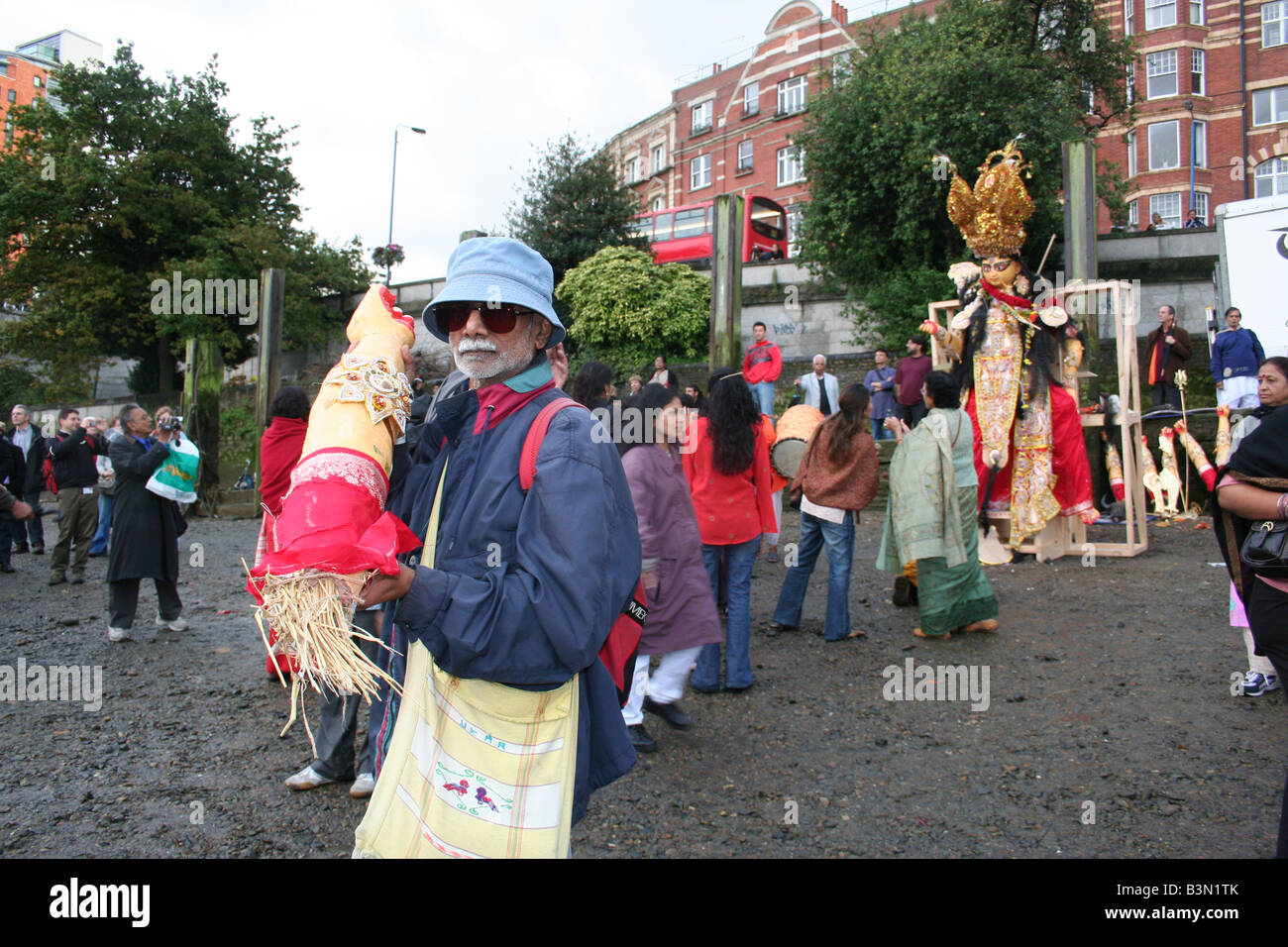 Mann mit abgetrennten Arm der Gottheit Durga für Immersion vor der Masse am Ufer des Flusses in Putney, London, England. Stockfoto