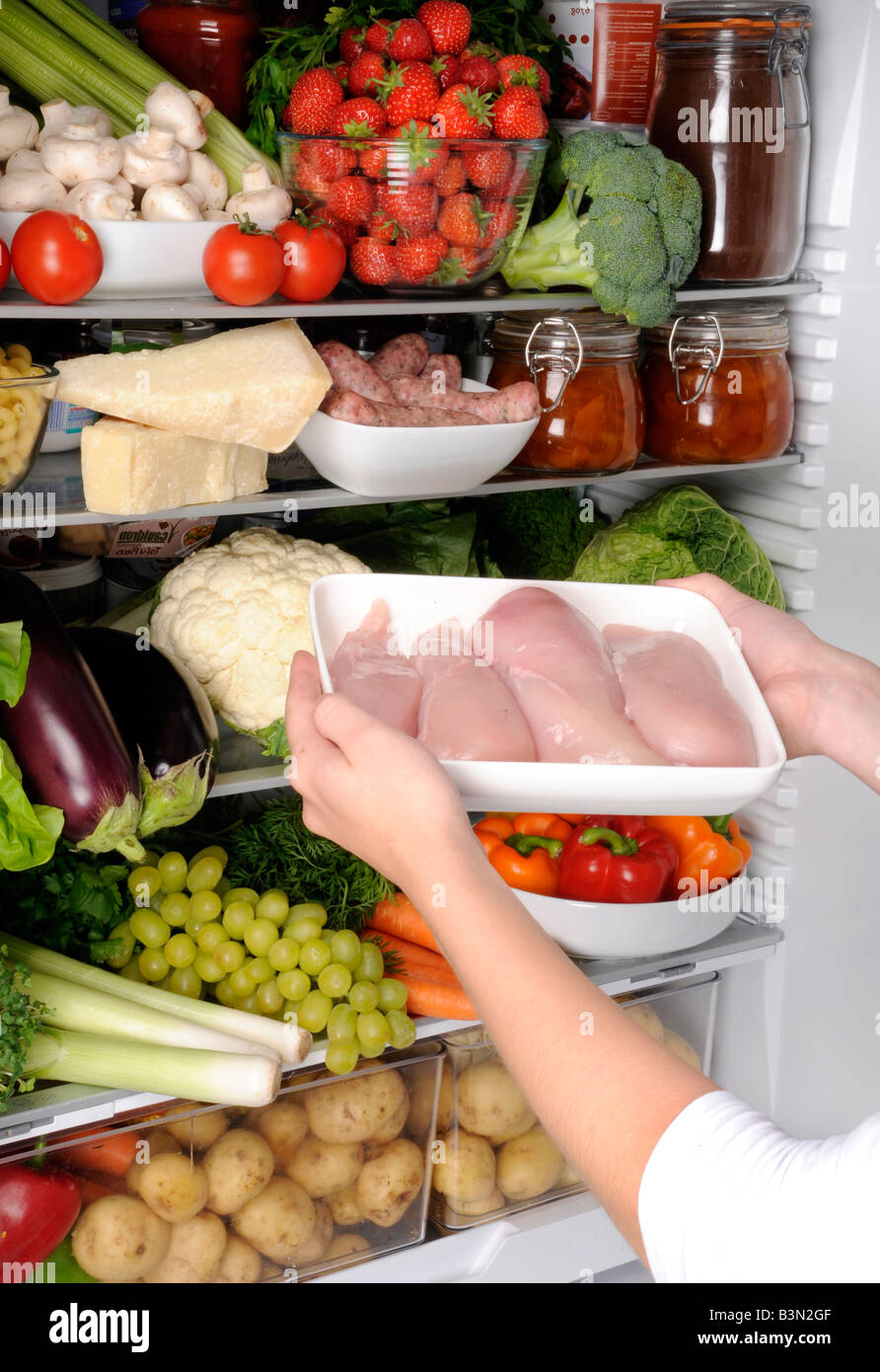 FRAU, HÜHNERFLEISCH IN KÜHLSCHRANK Stockfoto