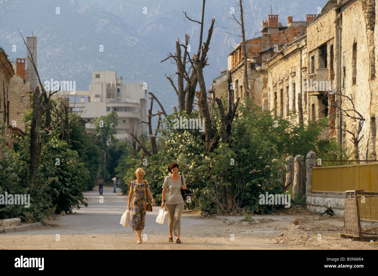 Mostar, Juni 1996', Leute zu Fuß entlang Boulevard Narode Revolucije, vorbei an Bäume beschnitten durch die Kämpfe, 1996 Stockfoto