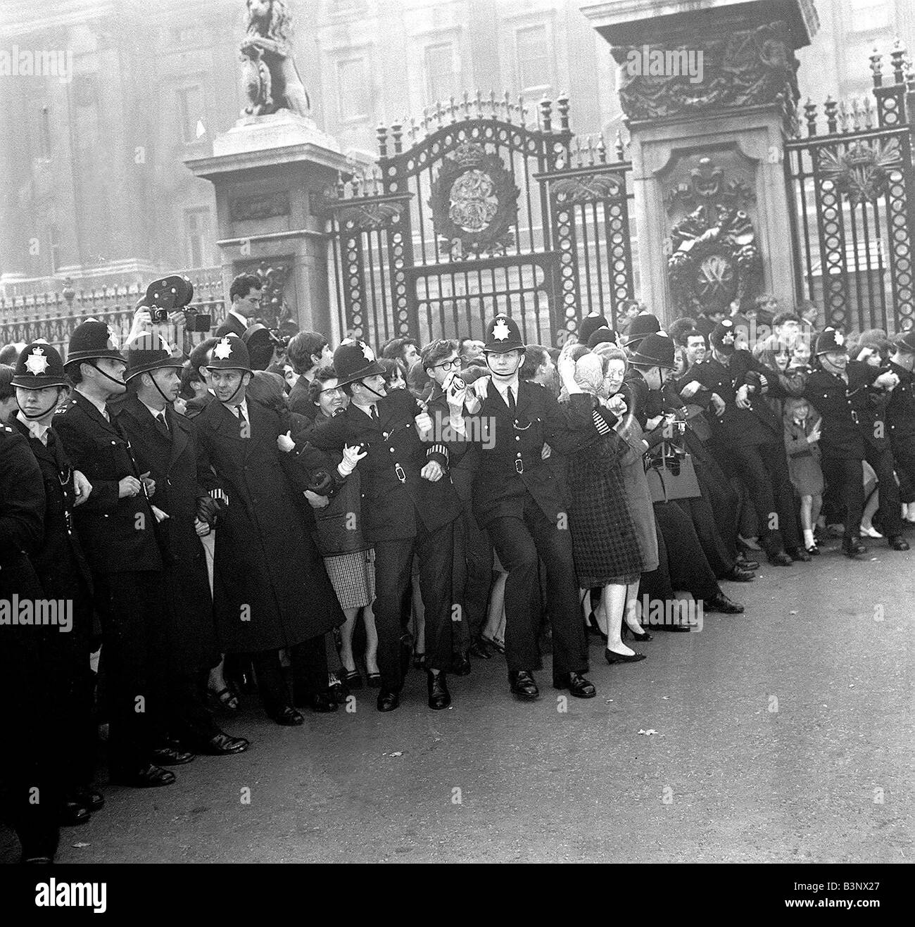 Polizei zurückhalten die Massen vor Buckingham Palast während sie darauf warten um einen Blick auf die Beatles, die ihre MBE-s erfassen Stockfoto
