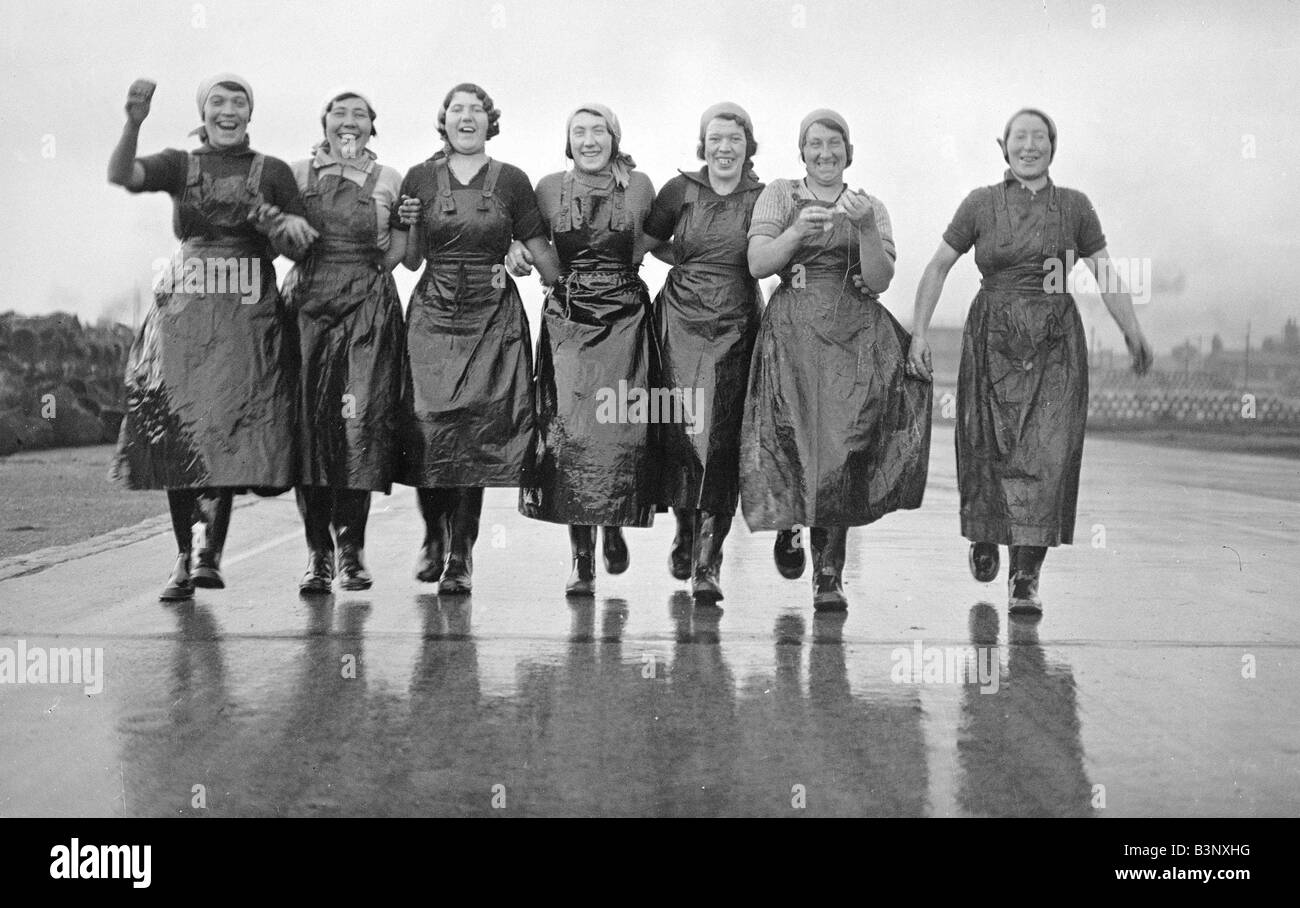 Great Yarmouth schottischen Hering Mädchen ca. 1936 Linkning Waffen auf dem Weg zur Arbeit Fische ausnehmen und Bodensenkungen vor allem Hering gefangen von der Fischereiflotte am Kai bei Great Yarmouth Stockfoto