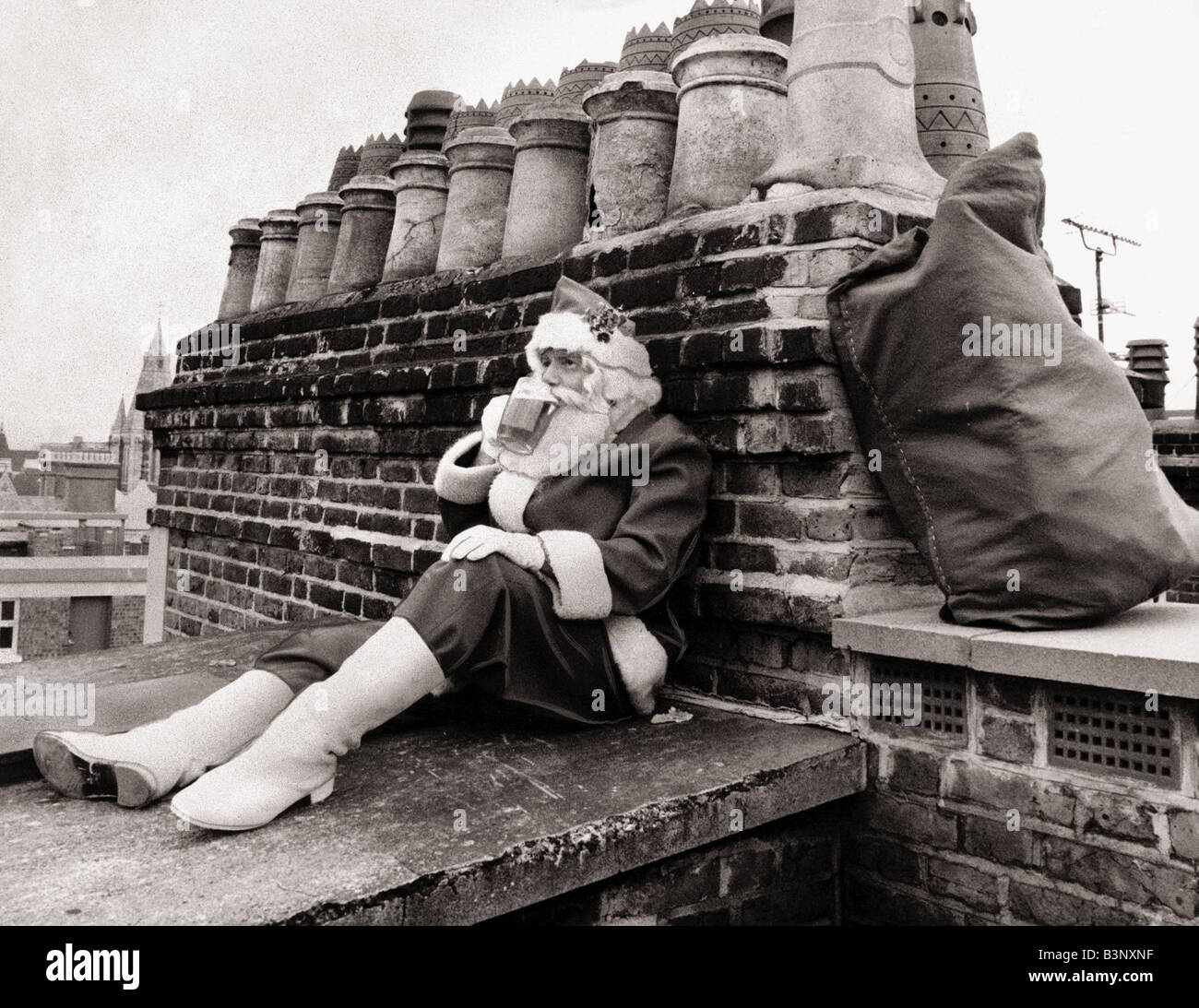 Vater Weihnachten Dezember 1986 versinkt Santa ein wohlverdientes Bier, als er nach einer Mitfahrgelegenheit nach Hause auf dem Dach des Stores Selfridges in London Weihnachtsmann Xmas Vater Weihnachten Weihnachten 1980er Jahren wartet Stockfoto