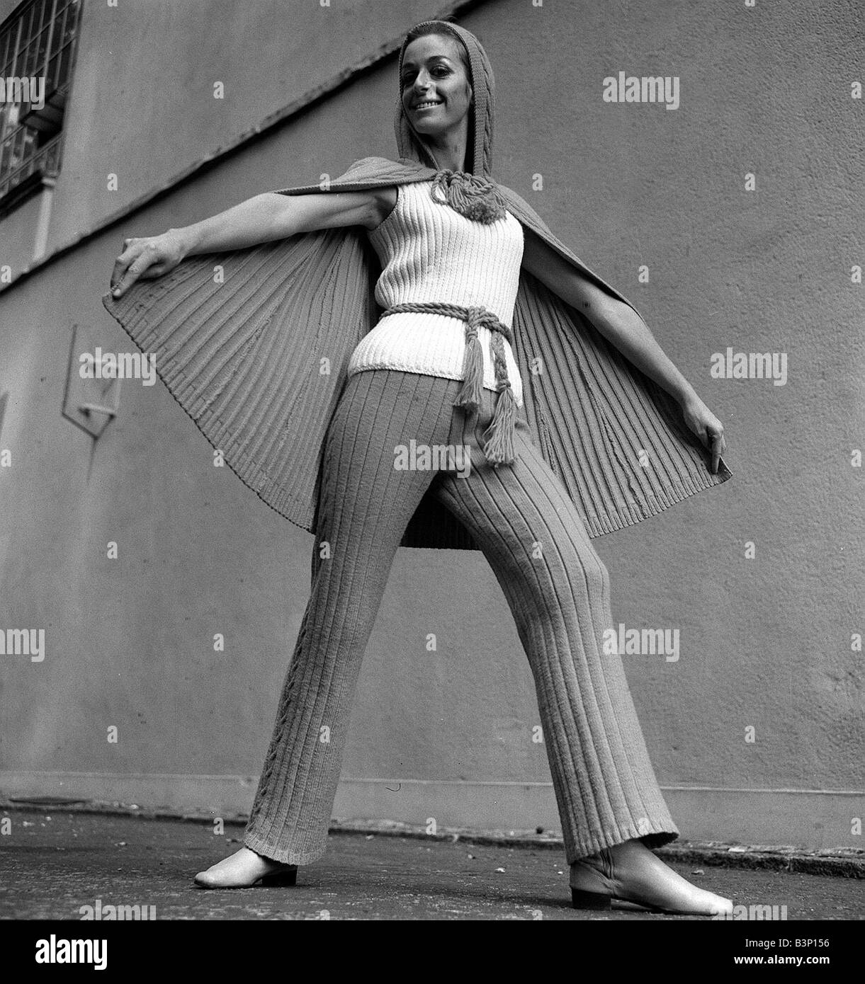 Mode-ICI 1969 Suzanne Gellard in Cape und Hose in Rasberry mit Pullover in Vanille stehend mit einem Fuß nach vorne und Arme Stockfoto
