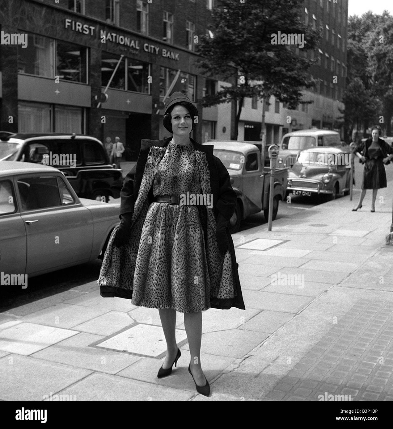 Norman Hartnell Herbstkollektion Juli 1962 Angela trägt einen Nachahmer voluminöse schwarze Tuch Mantel gefüttert mit mexikanischen Ozelot, eine Kleid komplett aus Fell mit einem schwarzen Ledergürtel zu offenbaren Stockfoto