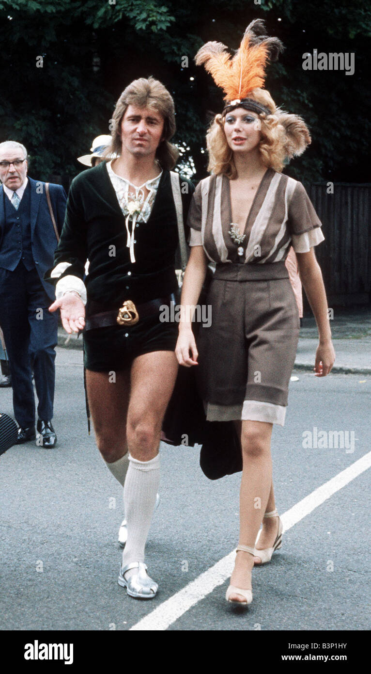 1971 besteht Kleidung Ascot Mode Hüte und Kleider paar seltsame ungewöhnliche Outfits Womans Hut aus drei orange Federn Stockfoto