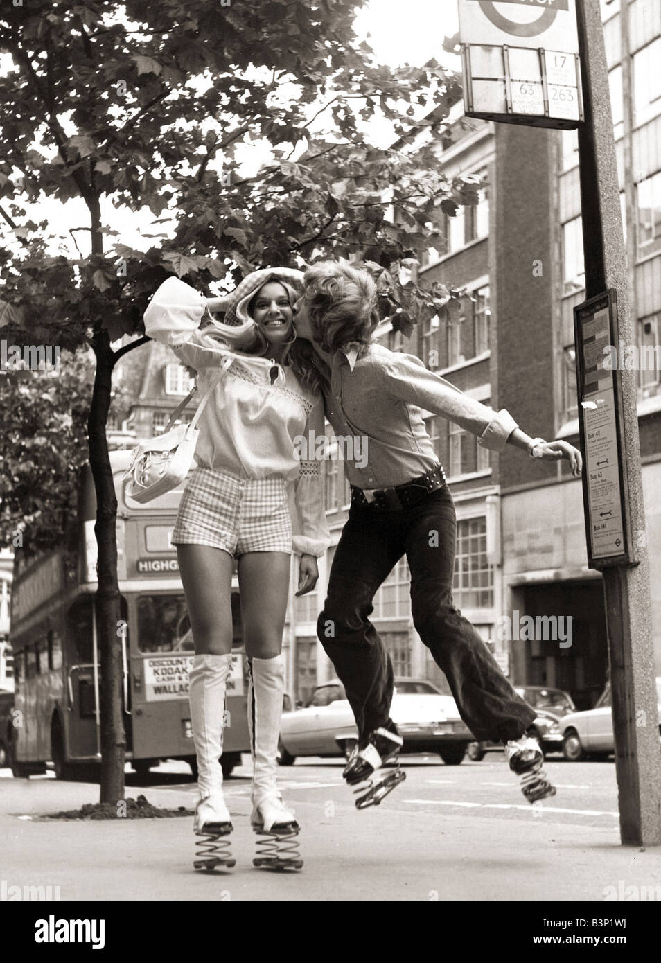 Nigel Lythgoe abgebildet in 1971 küssen ein Mädchen Heather Berkers mit Federn auf seine Schuhe beim warten an einer Bushaltestelle Juli 1971 Stockfoto