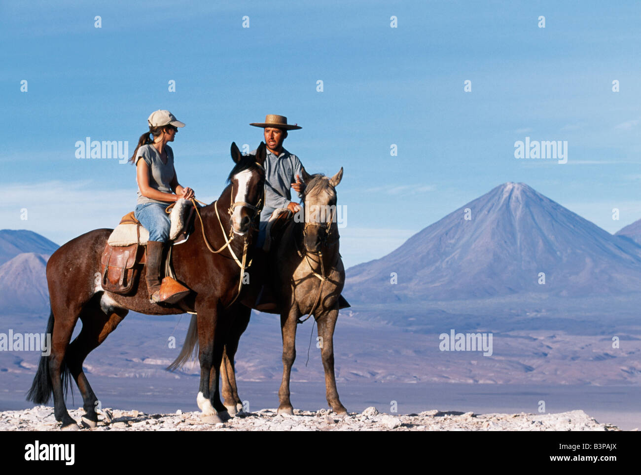 Chile, Atacama-Wüste. Im Chat während einer Pause in einem Pferd Trekking Las Cornicas Grat mit dem perfekten Kegel des Volcan Licancabur im Hintergrund Stockfoto