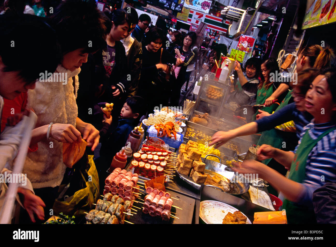 China, Hongkong, Kowloon. Kunden Line-up für eine Auswahl an Snacks auf den Straßen von Kowloon im Stadtteil Mong Kok Stockfoto