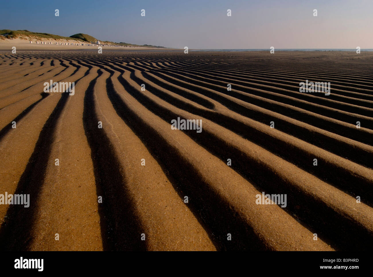 Abendstimmung am Strand mit Blick auf die regelmäßigen Wellen im Sand Strandkorb am Fuß der Dünen zu überdacht Stockfoto