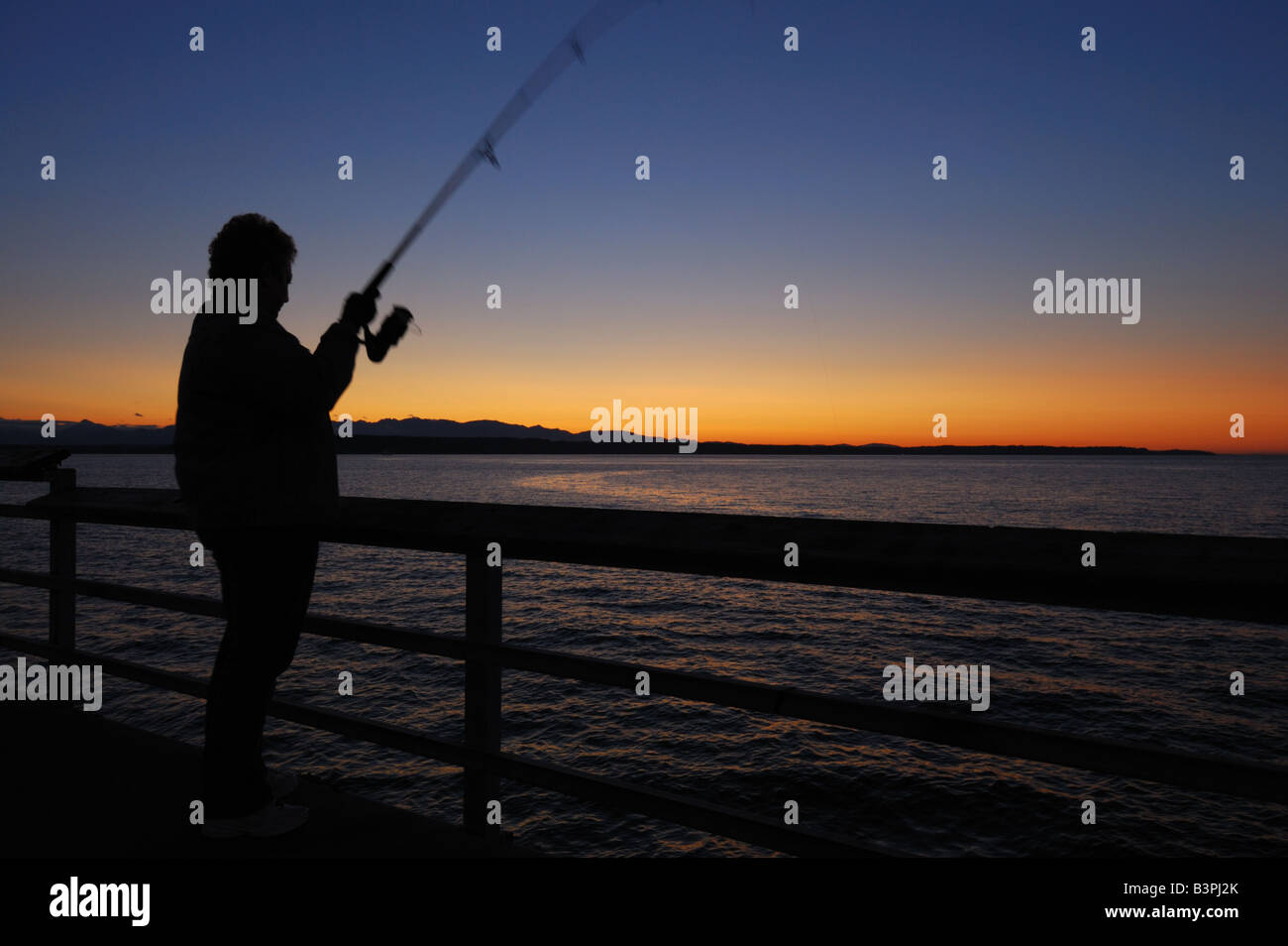 Eine Frau fischt für Lachs aus dem Edmonds, WA Fishing Pier. Stockfoto