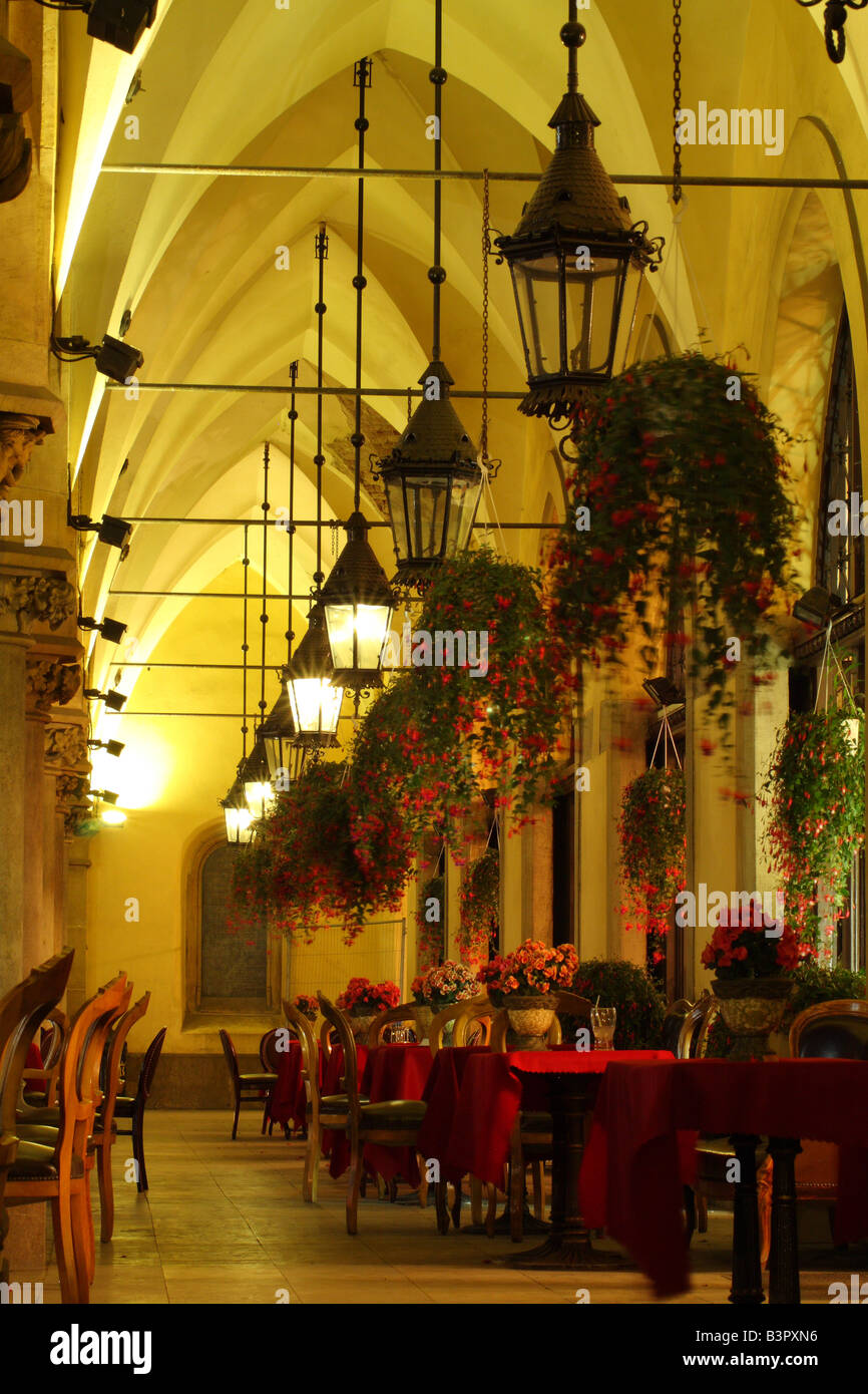 Verzierte Lampen hängen über dem Café-Tischen unter den Bögen der Tuchhallen (Sukiennice), Marktplatz, Krakau, Polen Stockfoto