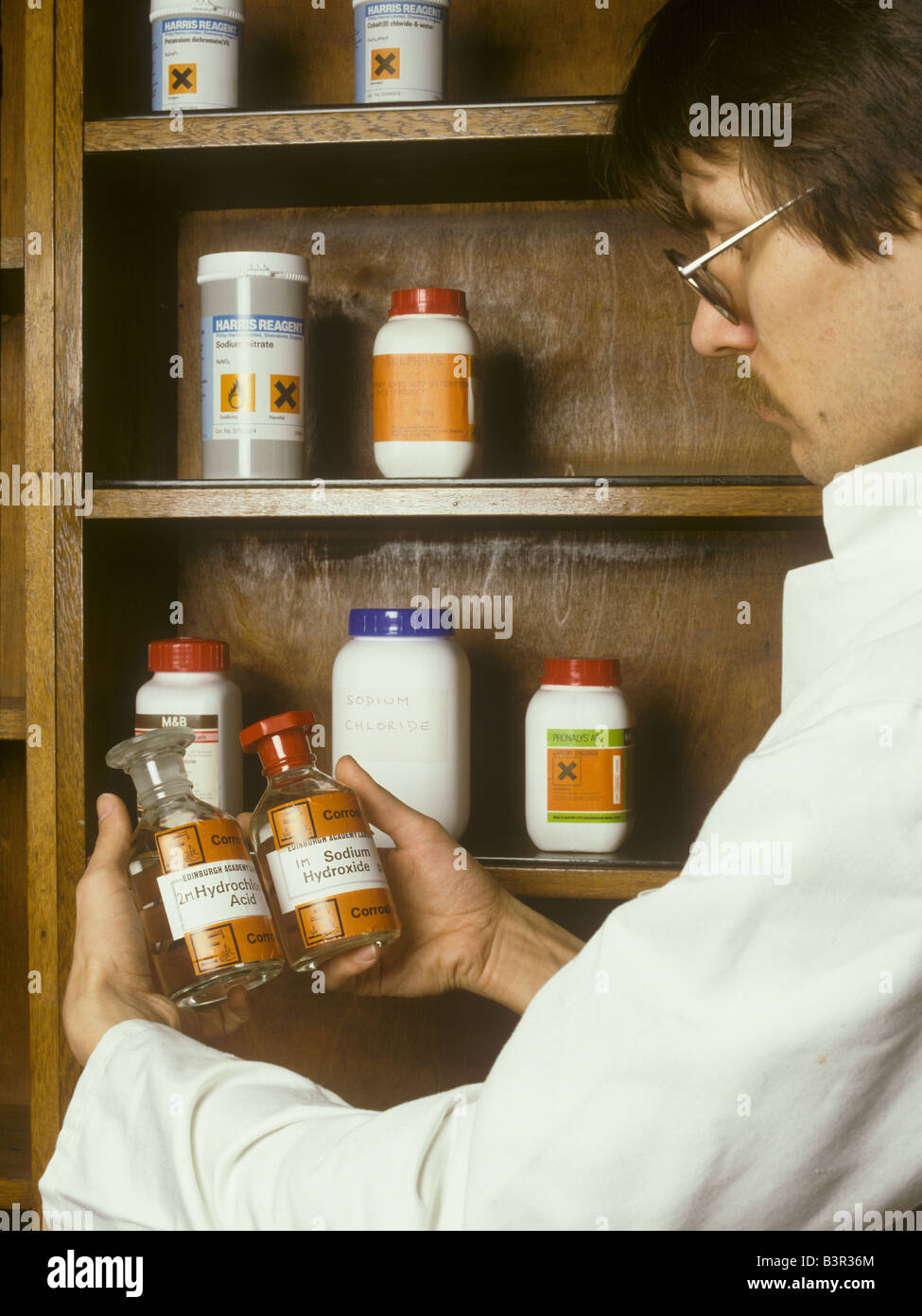 Laborantin fasst Reagenz Flaschen von ätzenden Chemikalien Stockfoto
