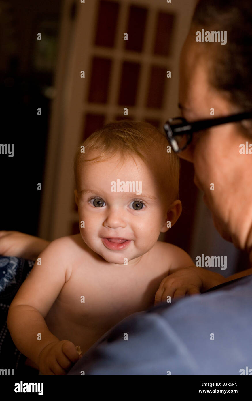 Mutter hält lächelnd acht Monate altes Babymädchen zu Hause Stockfoto