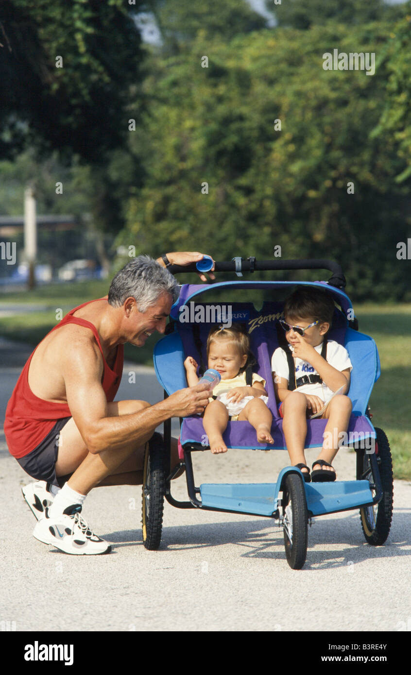 Vater mit 2 Söhnen in Kinderwagen im Park, Miami Joggen Stockfoto