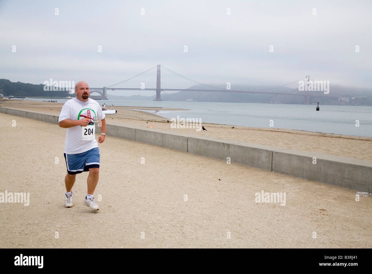 Läufer am Strand in der Nähe von Golden Gate Bridge Stockfoto