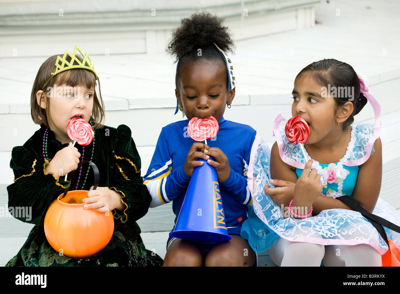 Kleine Mädchen, gekleidet in Halloween-Kostümen genießen ihr Lutscher. Stockfoto