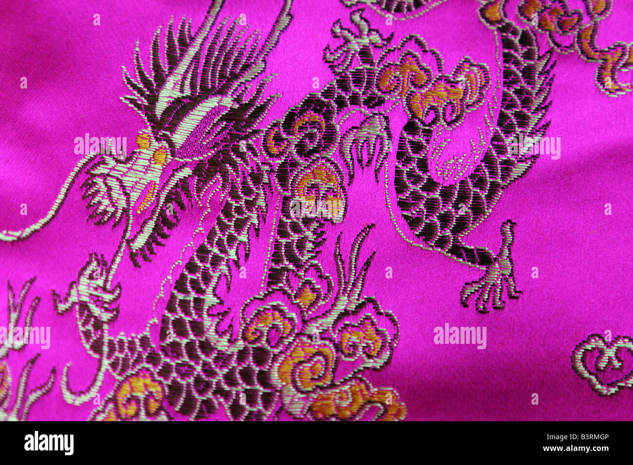 Chinesische Drachen auf rosa Seidenstoff Stockfoto