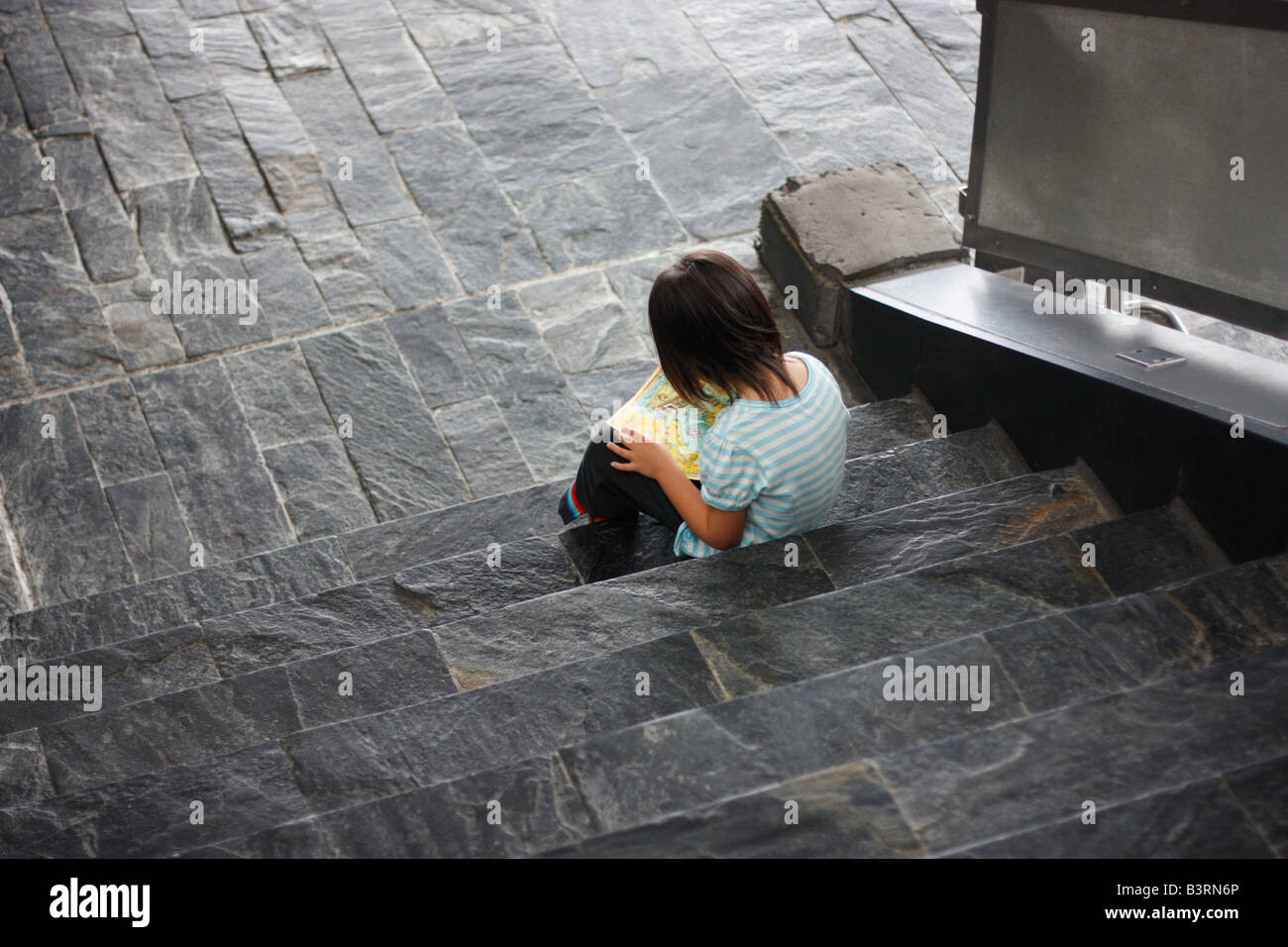 Vier Jahre altes Mädchen sitzen auf der Treppe Lesen einer Karte in einem Aquarium. Stockfoto