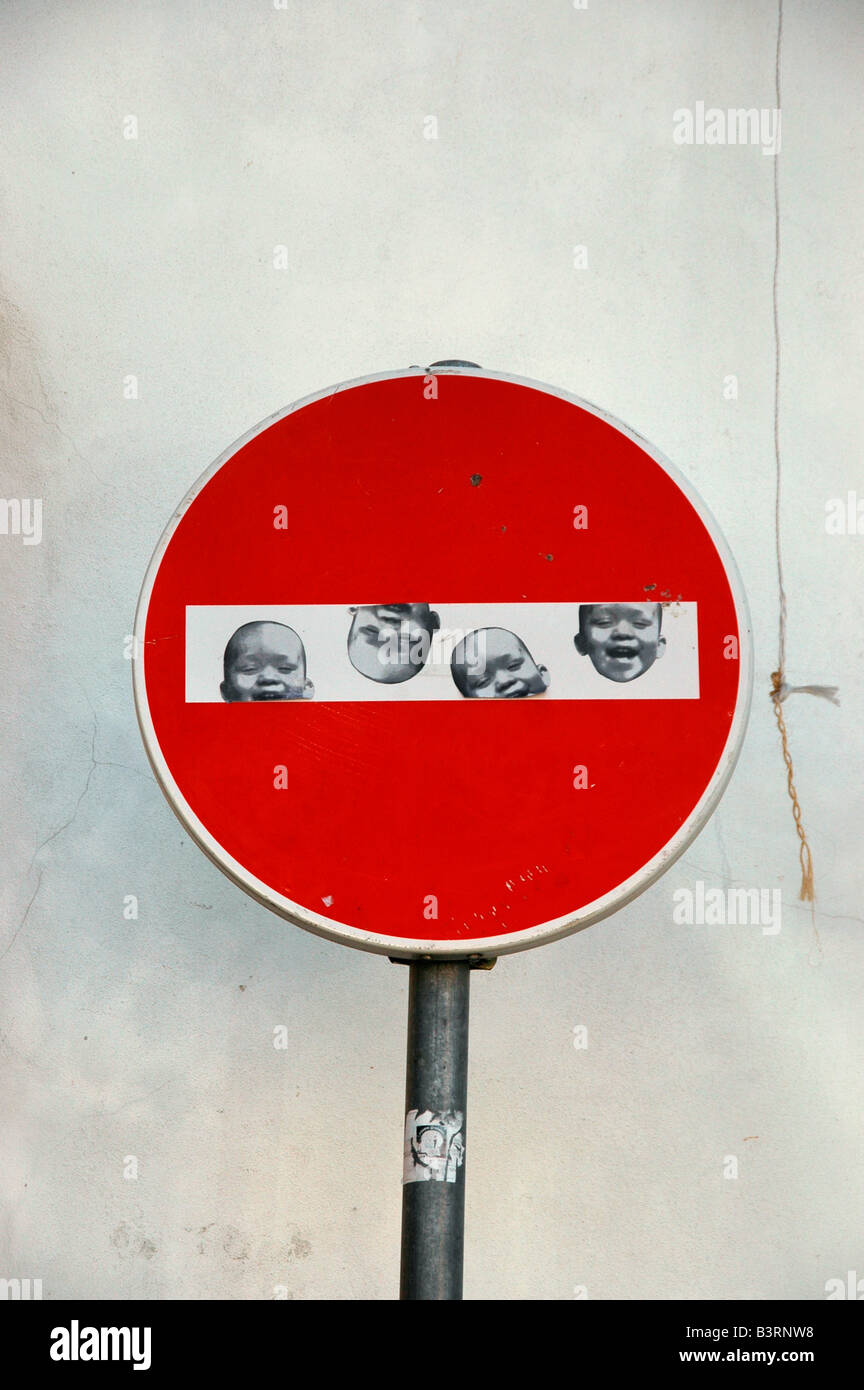 No Entry Zeichen gegen eine weiße Wand mit Bildern von einem lächelnden Baby Gesicht drauf. Stockfoto