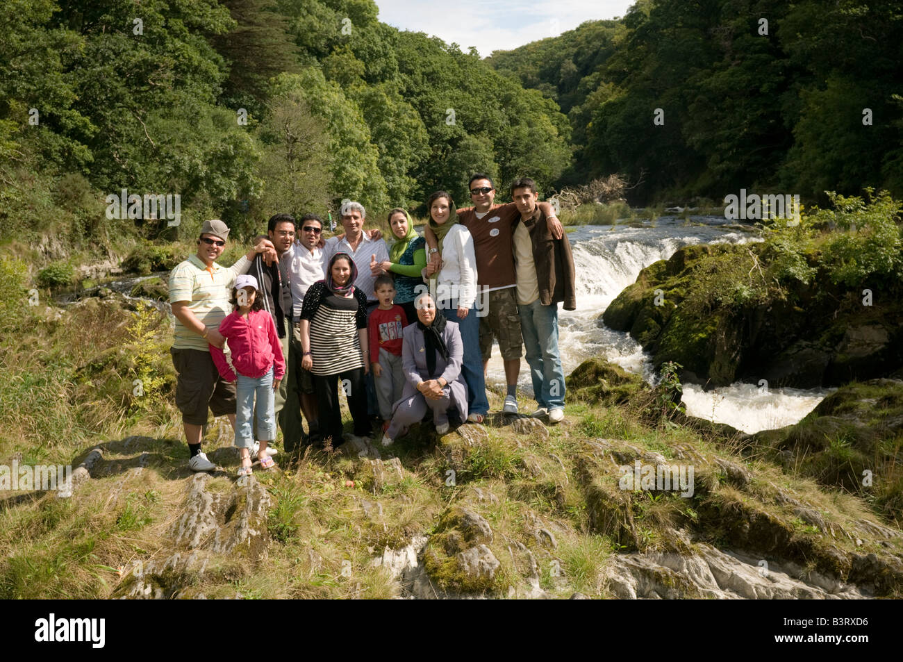 Indische Familie posiert für Foto vor der berühmten Wasserfälle bei Cenarth, West Wales, UK Stockfoto