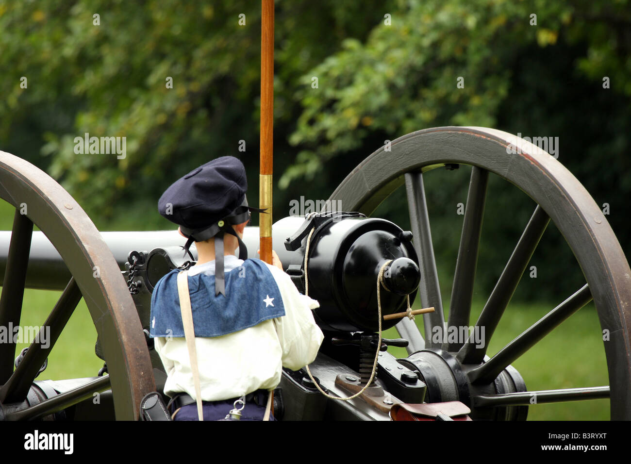 Ein kleiner Junge hält die Anschluß-Markierungsfahne vor einer Kanone im Feldlager Civil War Reenactment Stockfoto