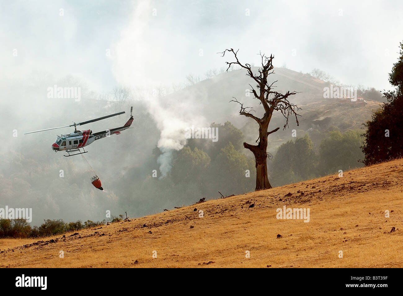 Ein California Department of Forestry Hubschrauber kehrt nach einem Sturz Wasser auf ein Lauffeuer Stockfoto