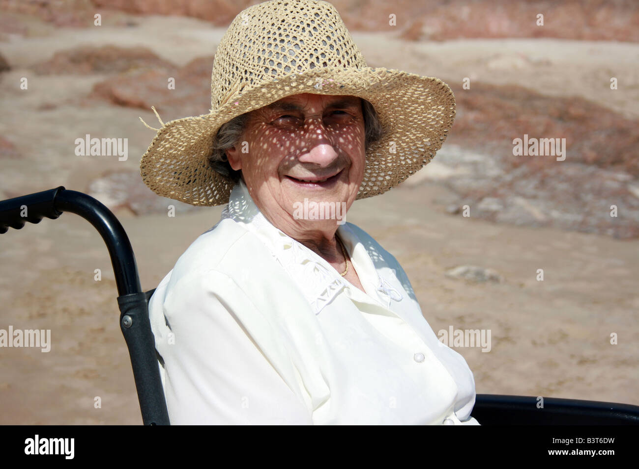 Eine alte Dame saß in einem Rollstuhl am Strand Stockfoto
