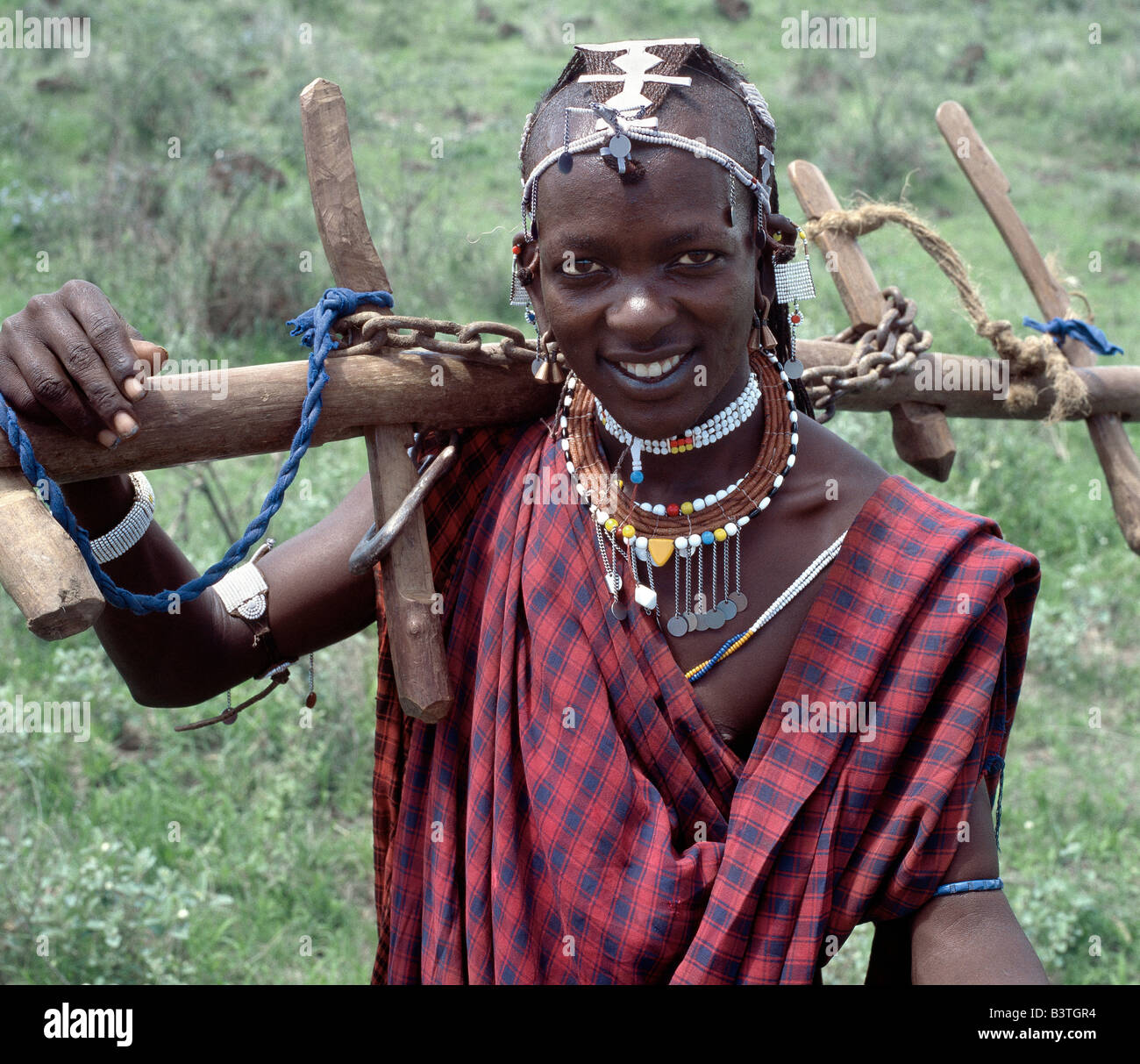 Tansania, Norden von Tansania, Mto war Mbu. Ein Wa-Arusha-Krieger trägt nach Hause ein Joch. Seine braune Halskette besteht aus aromatischem Holz. Die Wa-Arusha sind eng mit den Massai und sprechen die gleiche Sprache - Maa. Im Gegensatz zu den Massai bis sie jedoch das Land zu. In der Vergangenheit hat das sie in Konflikt mit ihren pastoralen Nachbarn gebracht, Anbau verschmäht. Stockfoto