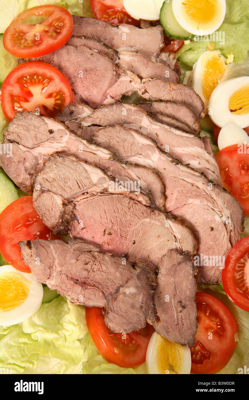 Eine Anzeige der Scheiben Lammbraten mit einem Salat aus Tomaten Gurke Ei und Salat Stockfoto