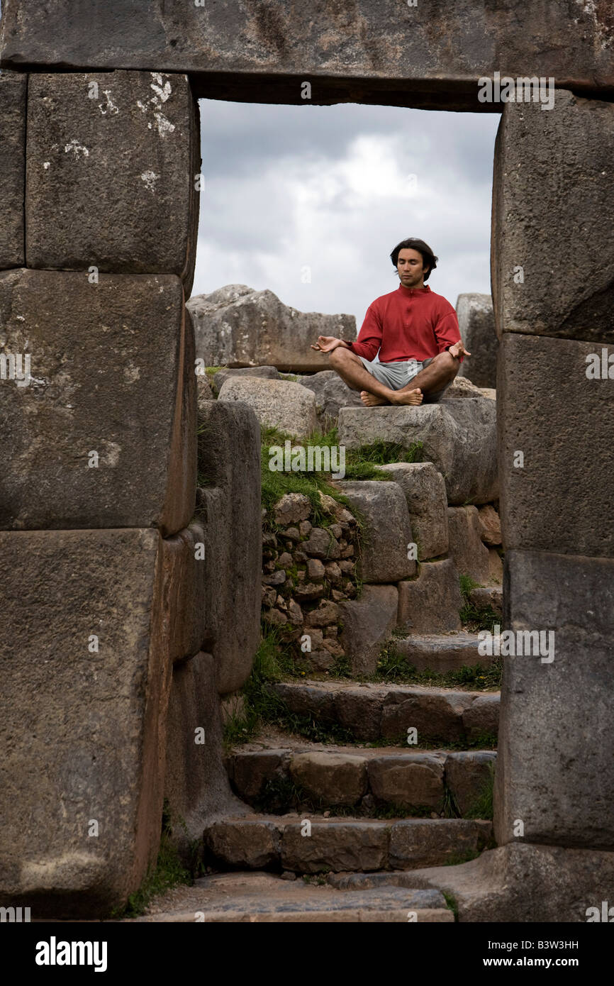 Ein junger Mann meditiert in alten Inka Ruinen außerhalb Cuzco, Peru Stockfoto