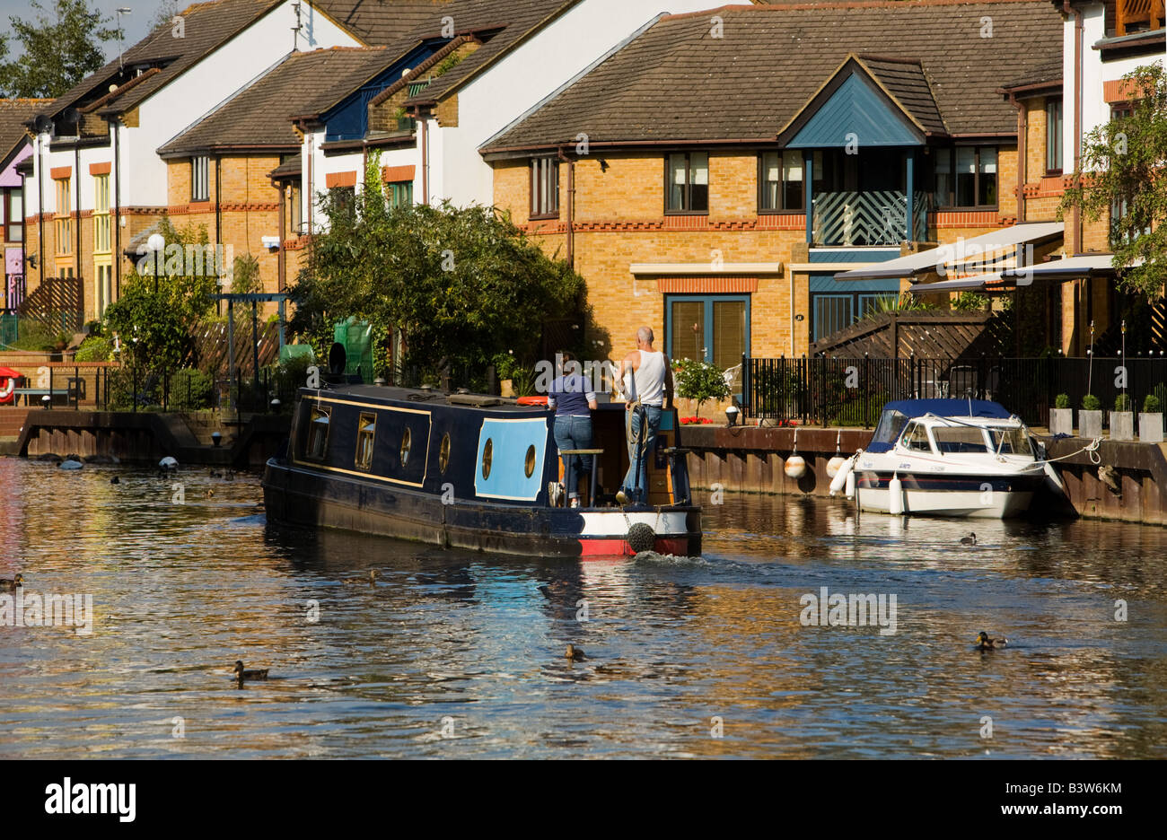 Schmale Boot vorbei am Wasser moderne Häuser und Gebäude am Grand Union Canal, Harefield in West London UK Stockfoto