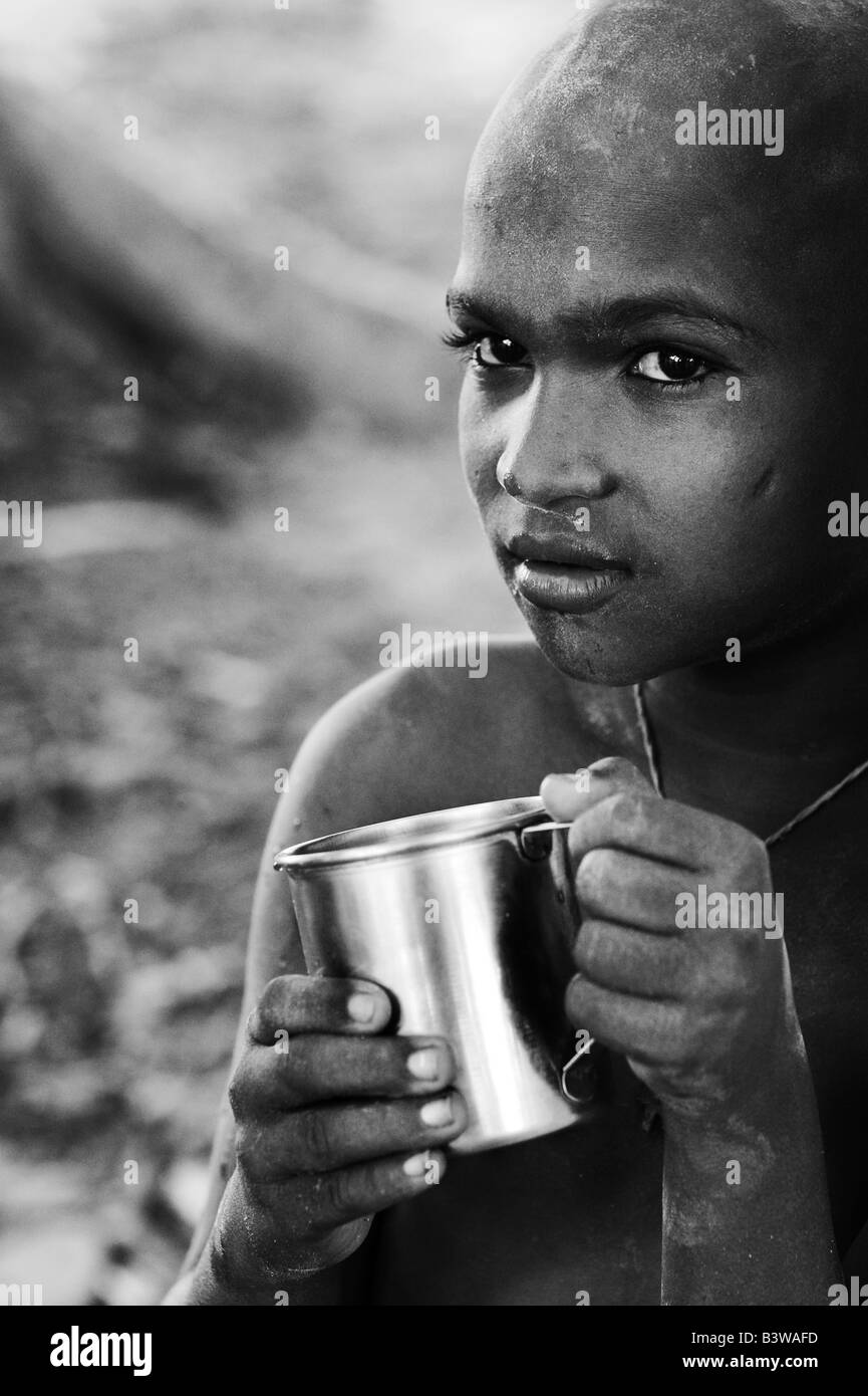 Armen indischen Jungen mit Metall-Becher, Wasser zu trinken. Schwarz / weiß Stockfoto