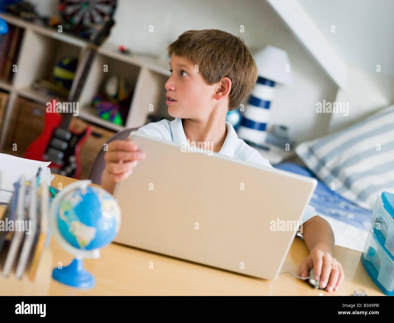 Kleiner Junge mit einem Laptop In seinem Schlafzimmer Stockfoto