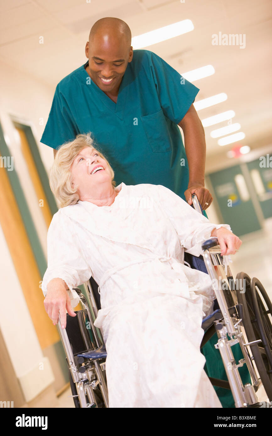 Eine geordnete schieben eine ältere Frau In einem Rollstuhl einen Krankenhaus-Korridor Stockfoto