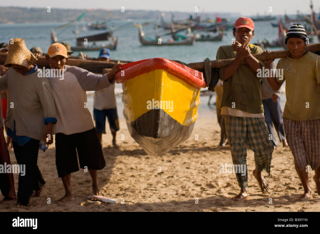 Fischer tragen ihre Boote aus dem Wasser s Rand nach einem Tag der Fischerei in Bali, Indonesien Stockfoto