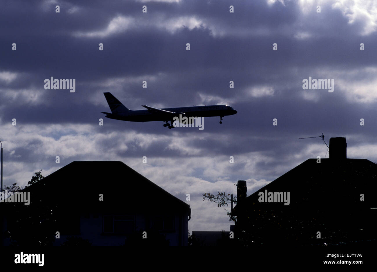 Ein Flugzeug fliegt über Häuser neben Heathrow Flughafen uk Stockfoto
