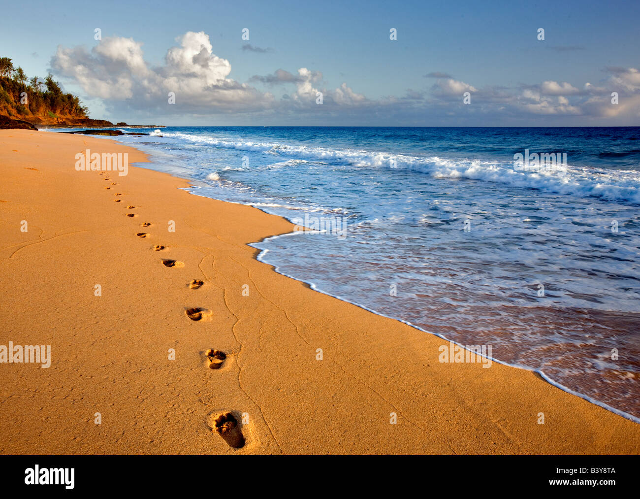 Sonnenaufgang am Secret Beach mit Fußspuren im Sand Kauai Hawaii Stockfoto