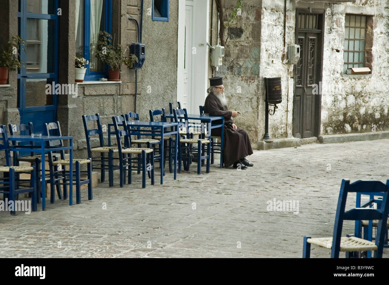 Griechisch-orthodoxe Priester ruht in einem Café in einem griechischen Dorf. Stockfoto