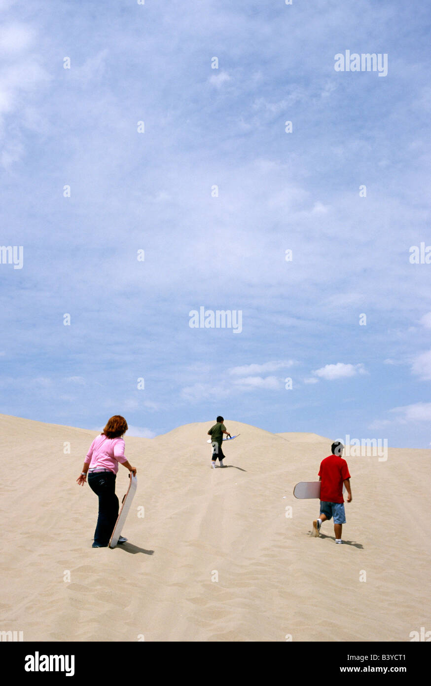 Peru, Ica, Huacachina. Eine Familie skaliert die Dünen für einige Sandboarding, in der Nähe von Huacachina im Süden Perus. Vom Oasis village Stockfoto