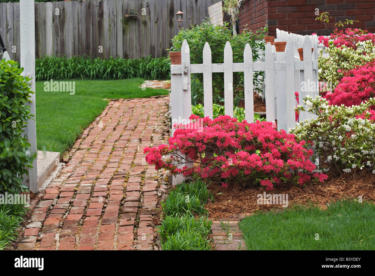 Ziegel Bürgersteig, Pickett Zaun und Azaleen, Audubon Park Nachbarschaft, Louisville, Kentucky Stockfoto
