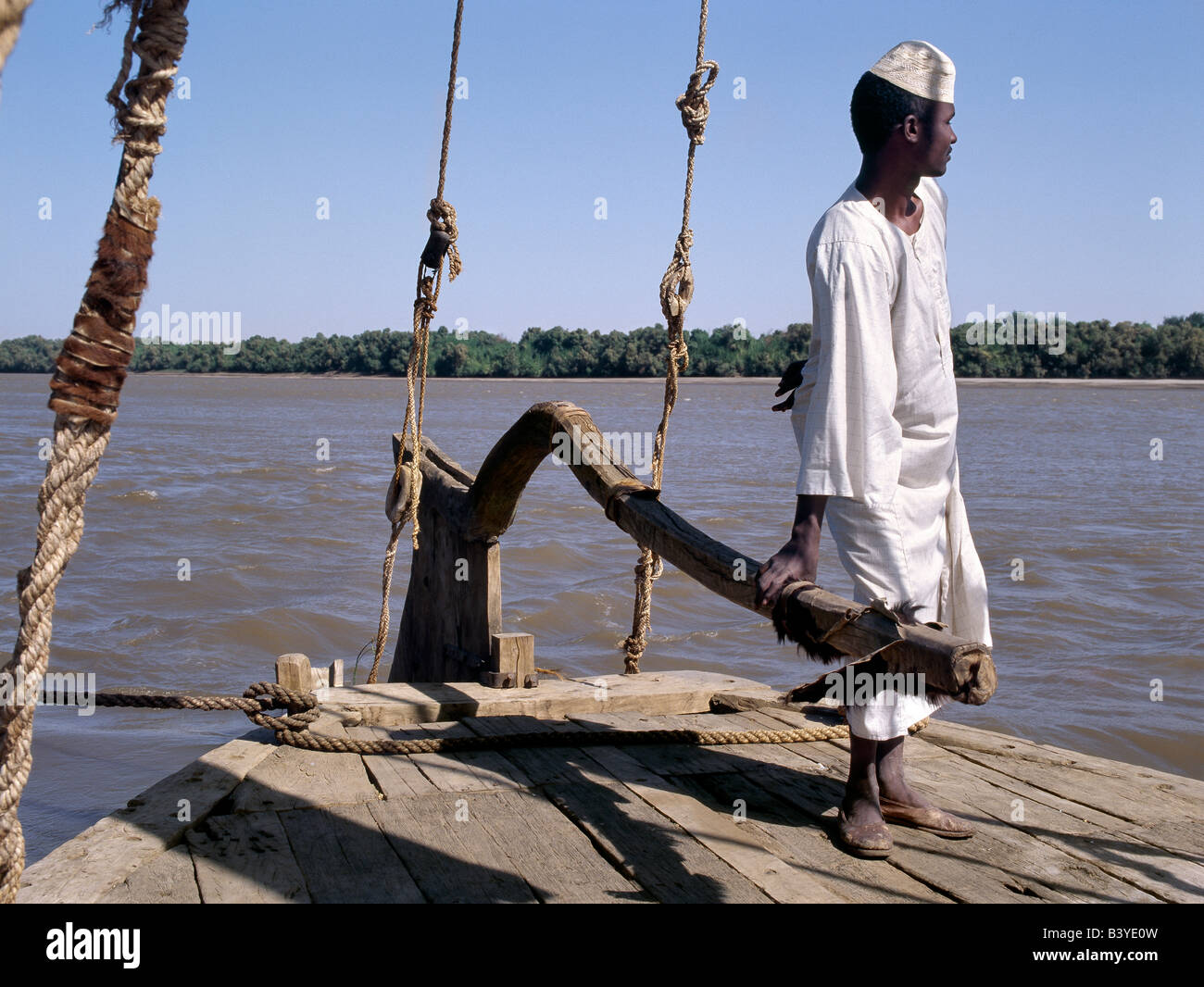 Sudan, Delgo. Eine nubische Bootsmann an der Spitze seiner Feluke, einem hölzernen Segelboot, die das Wasser des Nils in Ägypten und Sudan lagen. Stockfoto