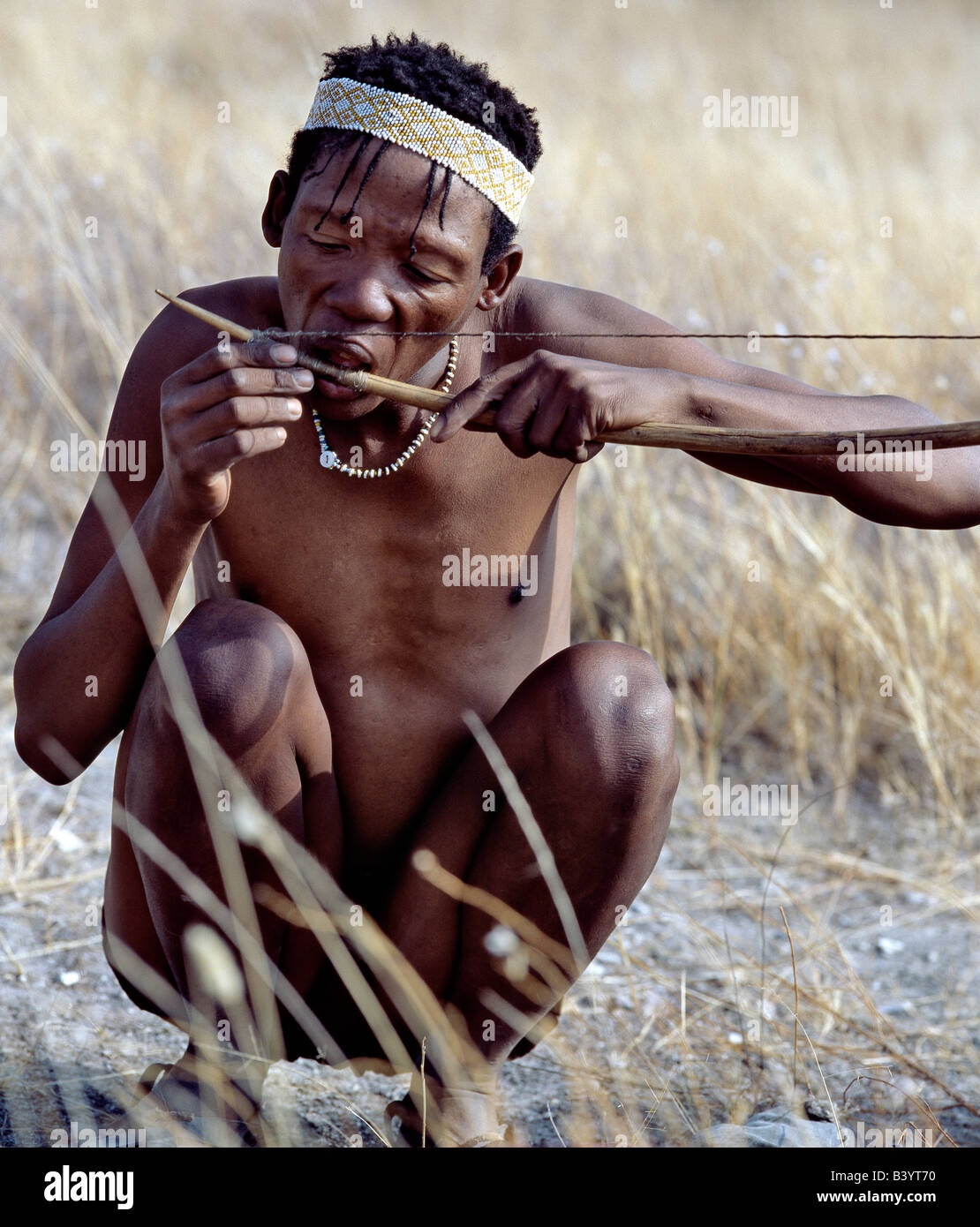 Namibia, östliche Buschmannland, Tsumkwe. A! Kung Jäger-strafft seine Bogensehne mit Händen und Zähnen.  Die! Kung sind ein pa Stockfoto