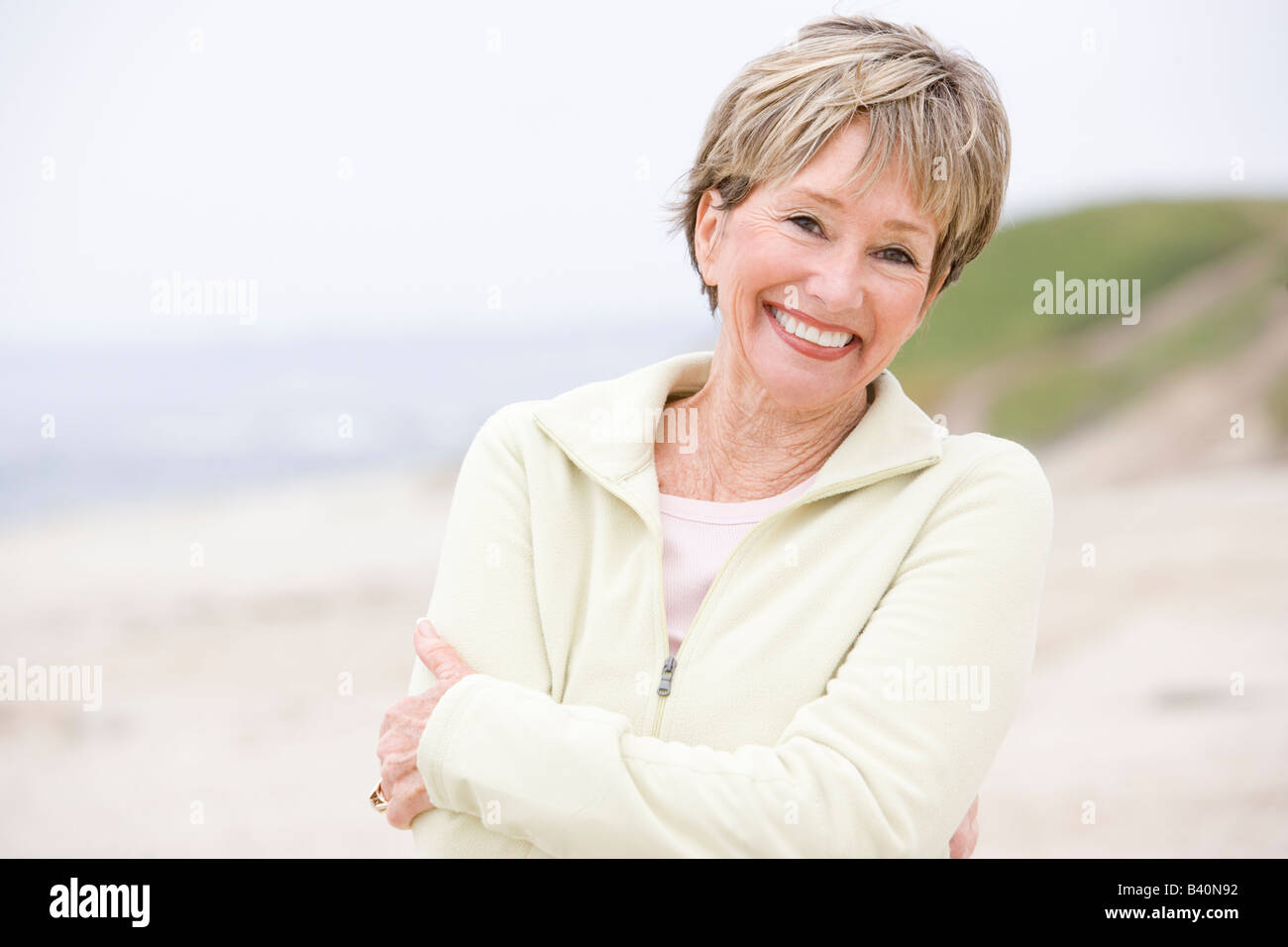 Frau am Strand mit verschränkten Armen lächelnd Stockfoto