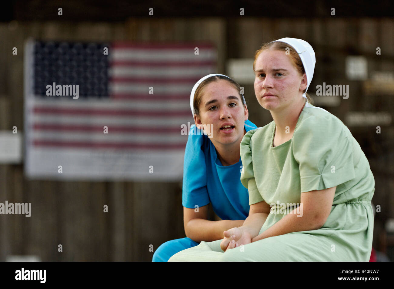 Mennonite Mädchen im Teenageralter sprechen am Erbe-Festival mit amerikanischen Flagge hinter Lanesville Indiana Stockfoto