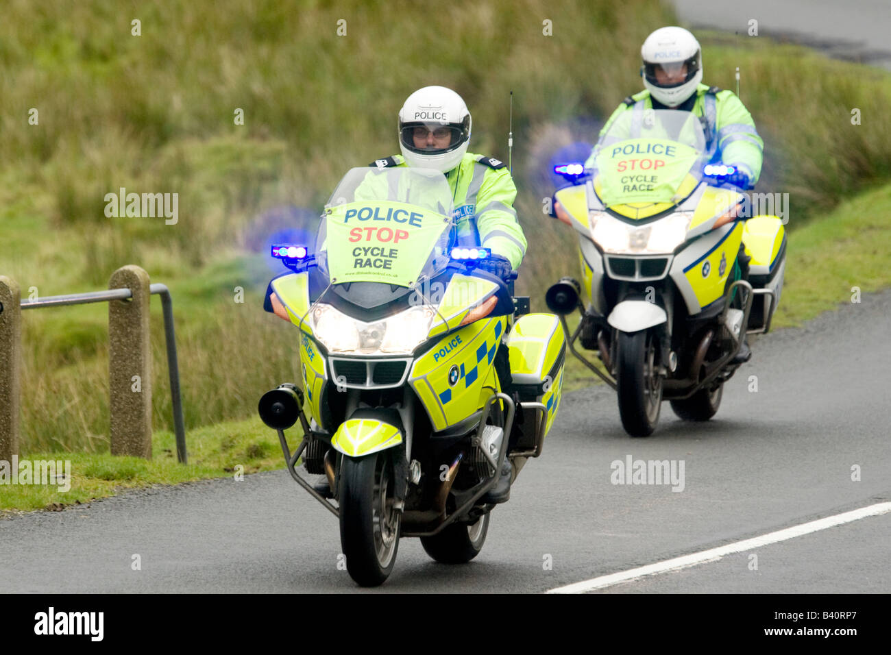 Zwei Motorrad-Polizei-Motorradfahrer mit Blaulicht begleitet die Tour of Britain Radrennen bis Mennock Pass Scotland UK Stockfoto